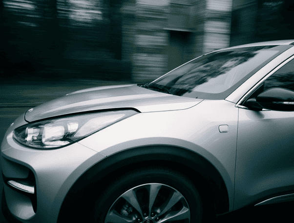 Передняя часть серебристого кроссовера Kia на дороге